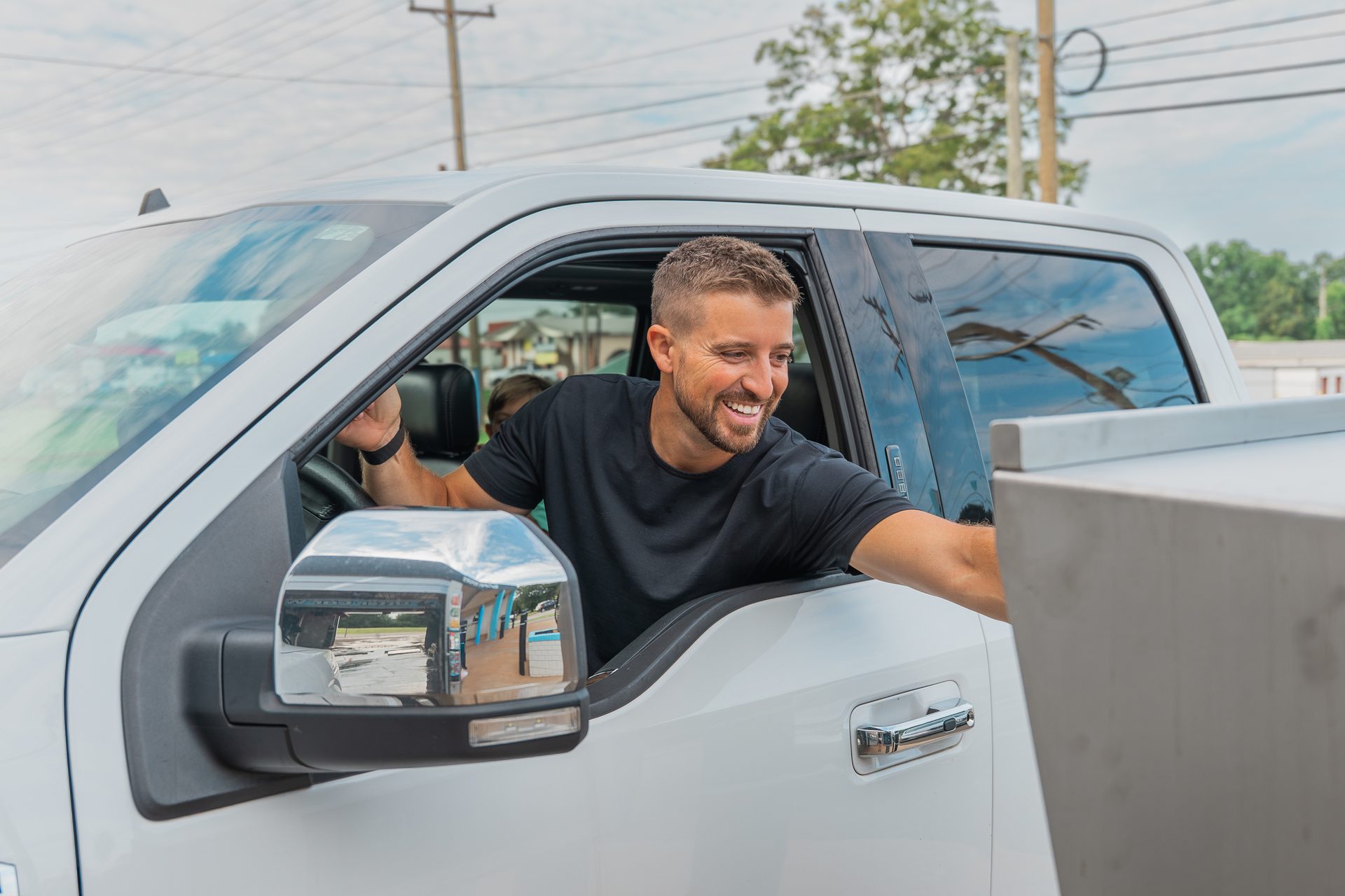 Smiling driver leaning out of his truck window at the Otter Car Wash kiosk